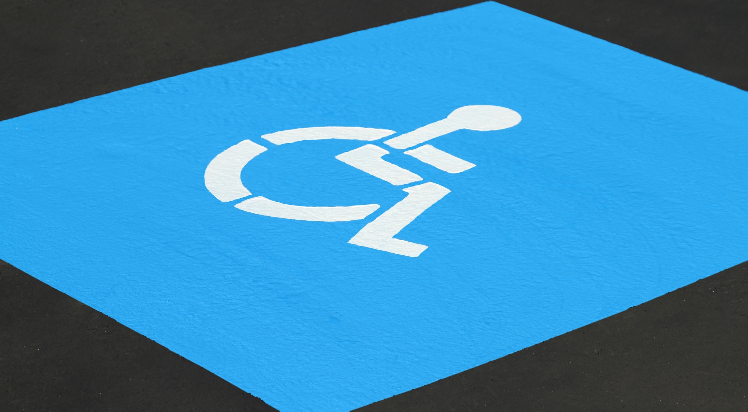 Pintura de señalización vial azul para personas con discapacidad SealMaster, homologada según la ADA, en un aparcamiento