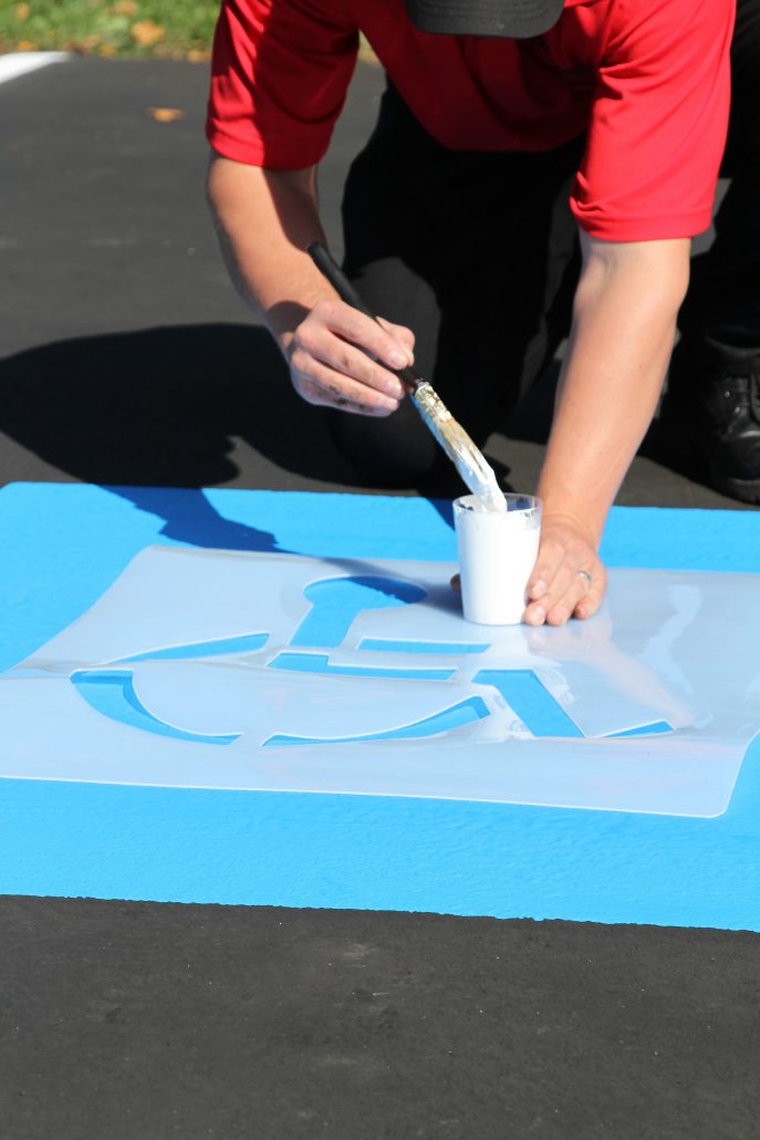 Applying traffic marking paint to a handicap parking spot on a parking lot. Learn how to stripe a parking lot.