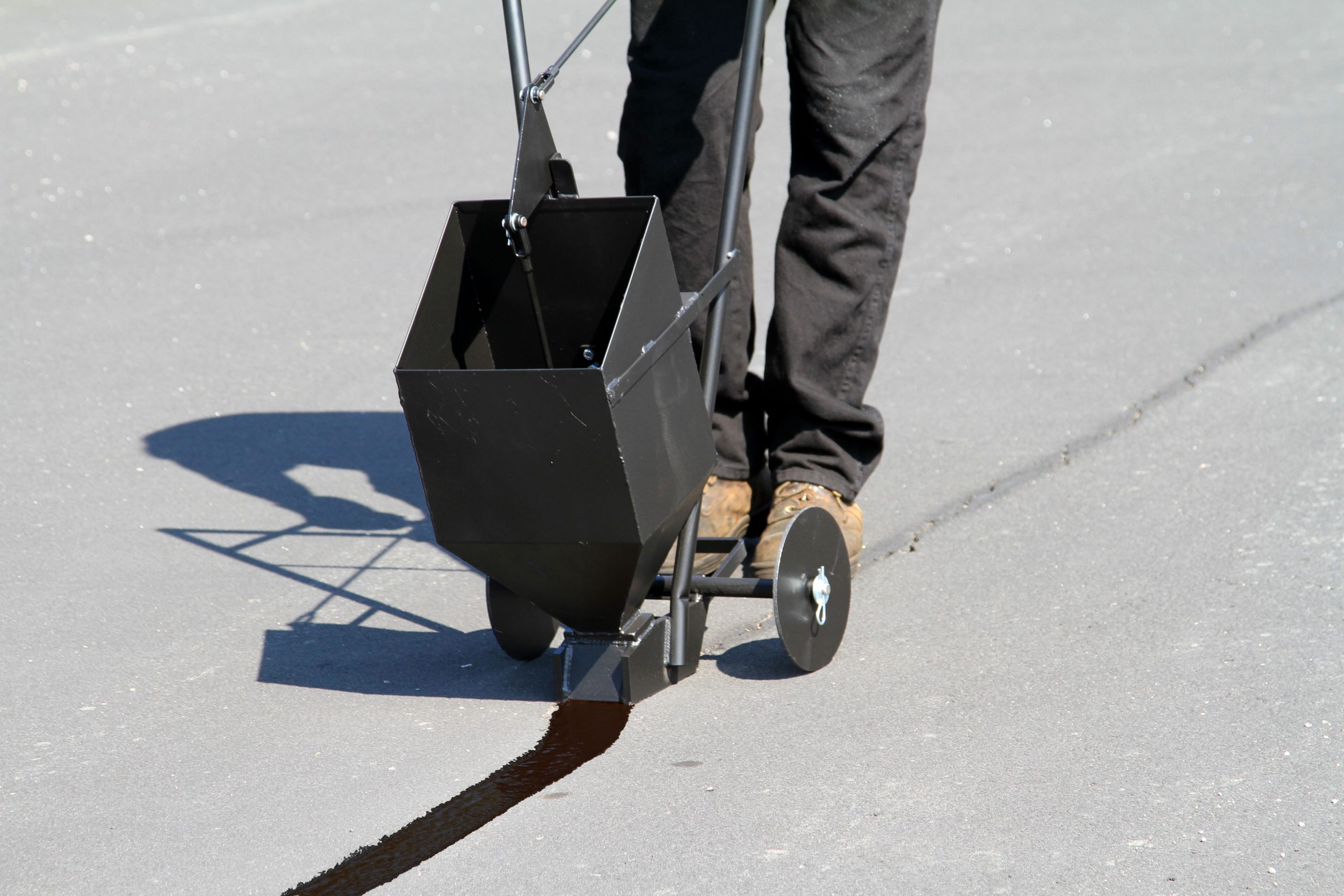 Applying Rubberized Pourable Crack Sealant | SealMaster Applying Rubberized Pourable Crack Sealant using a crack bander on a parking lot.