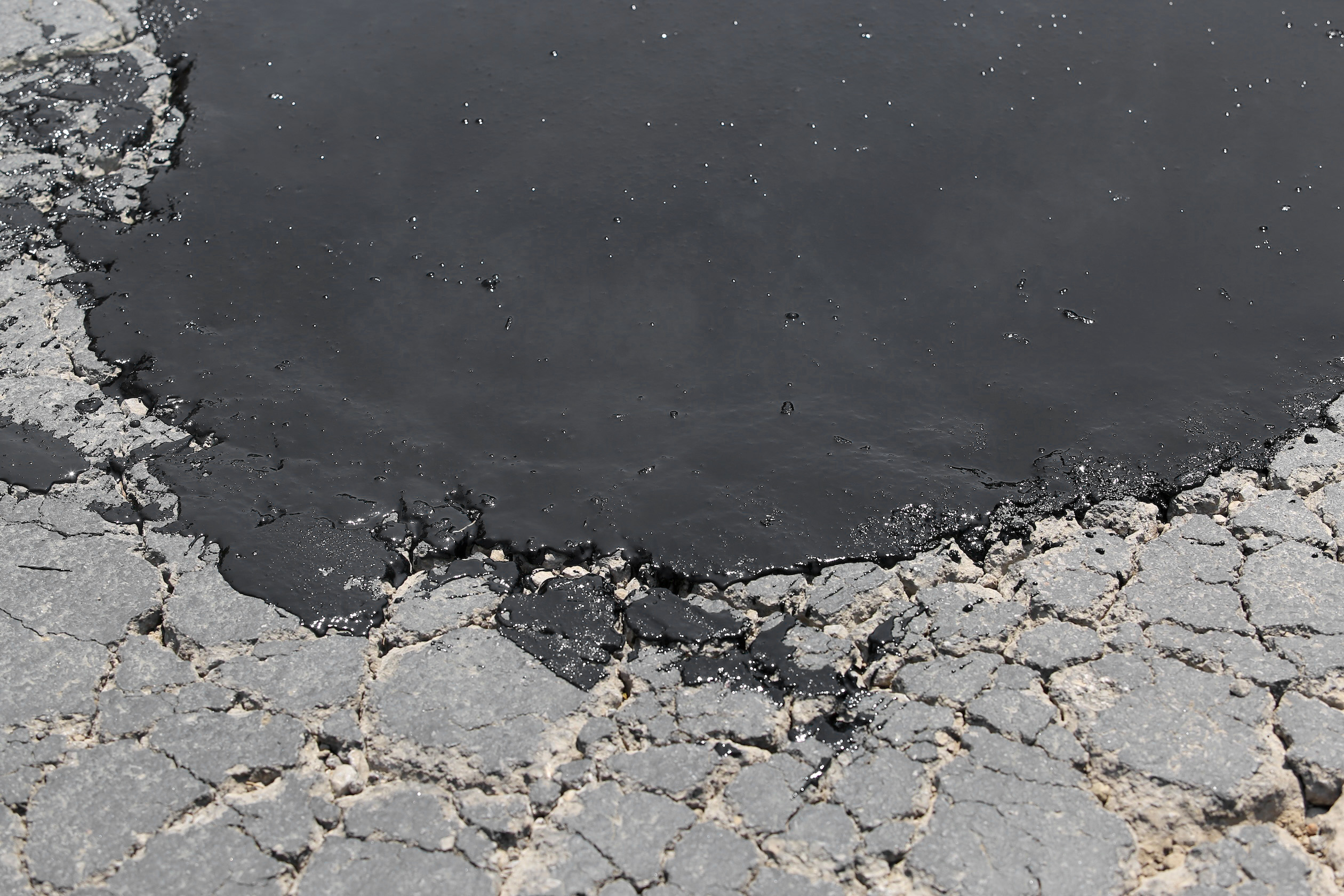 Hardened mastic on distressed pavement. Hardened mastic on distressed pavement.