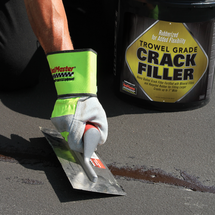 SealMaster Trowel Grade Crack Filler being applied to a crack in a parking lot.